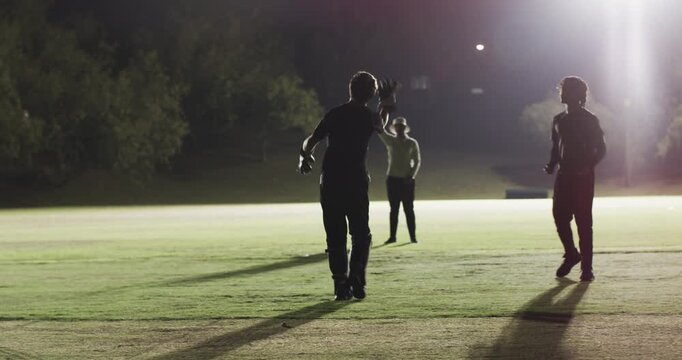 Non-striker signaling bowler delivering, batter defending, partners celebrating under floodlights