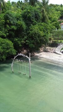 Aerial viwe of a swing set standing in shallow turquoise water at Weh Island Sabang, Indonesia. The Hawk Nest beach resort.