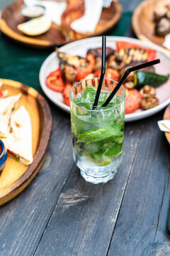 Refreshing summer mojito cocktail with ice and lime slices on an outdoor restaurant table