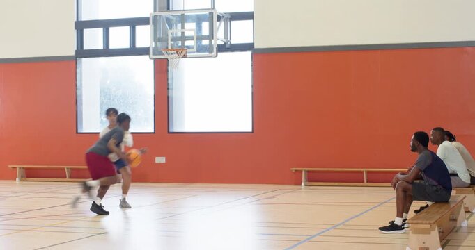 Entering gym half-court, african american player executing crossover layup