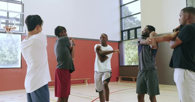 Starting stretch, diverse male friends pulling arms over chests at basketball court