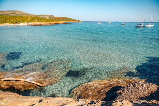 Rugged rocky cliffs overlook crystal clear blue water along the coast of North Corsica France