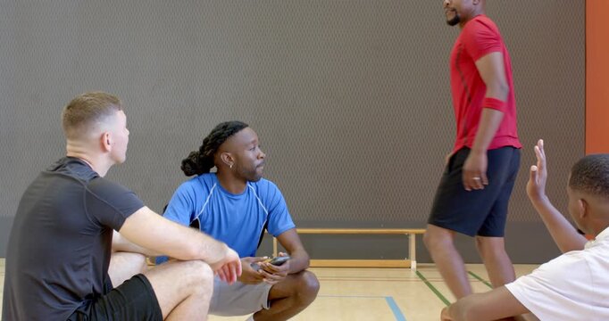 Ending break, diverse male players fist bumping, grabbing water bottle, resuming strategy at court