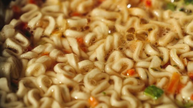Close-up of noodle soup served in flavorful broth with spices and herbs. Traditional homemade dish, Asian-inspired cuisine. High quality 4k footage