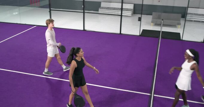 After point win diverse padel opponents high-fiving, handshaking and preparing rematch on court