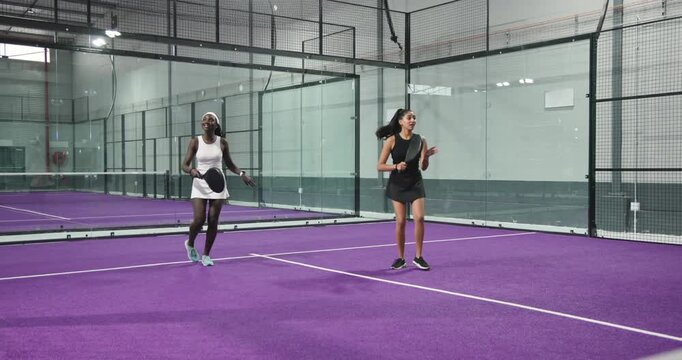 After lob african american woman with indian friend volleying ball celebrating on court