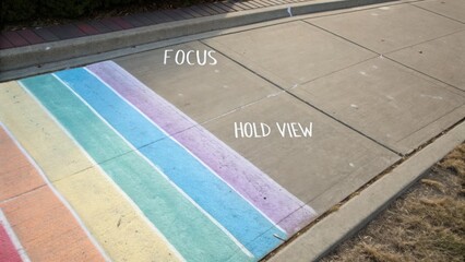Fototapeta premium Colorful chalk art on sidewalk showcasing vibrant rainbow stripes in urban environment with playful handwritten text and textured concrete surface
