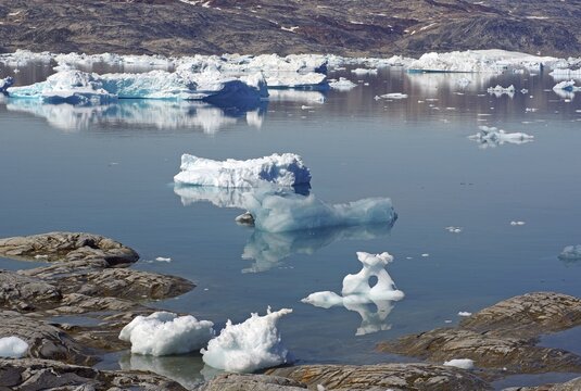 Ice floes are reflected in calm, clear water in an arctic landscape, Tiniteqilaaq, Tasilaq, Greenland, Denmark