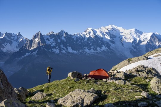 Photographer with telephoto lens next to red tent, mountain landscape in the morning light, mountain peak of Mont Blanc, Mont Blanc massif, Aiguilles Rouges, Chamonix-Mont-Blanc, Haute-Savoie, France
