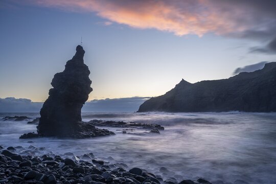 Sunrise on the beach at Playa de La Caleta with Punta San Lorenzo. Rocks and sea. Coloured clouds in the sky. Long exposure. La Gomera, Canary Islands, Spain