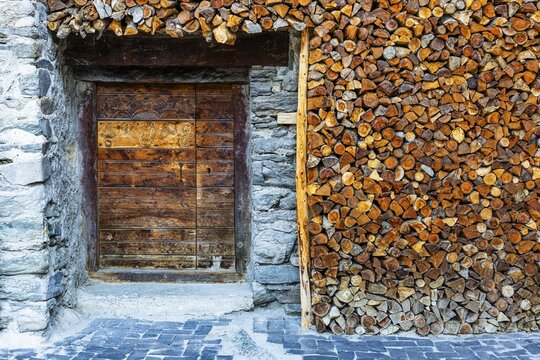 Entrance to a wine cellar framed by firewood logs, historic village centre, Grimentz, Val d'Anniviers, Valais Alps, Canton Valais, Switzerland