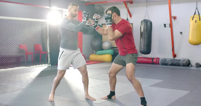 Diverse male fighters feinting trading jabs clinching sprawling and pinning against wall