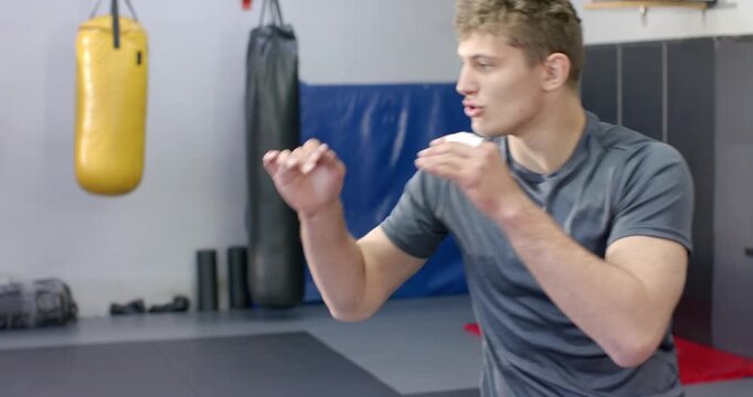 After bounce adult male striking heavy bag at gym wrapping wraps working footwork smiling