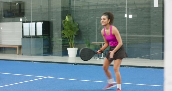 Following serve, female teammates lunging, blocking on paddle court, tapping paddles