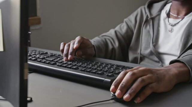 Close-up shot of unknown African American male programmer typing on keyboard and using computer mouse in office. Footage for software development, IT training, and tech startup marketing campaigns