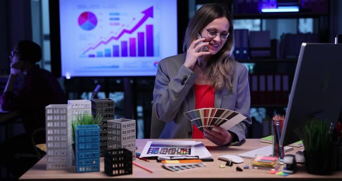 Female architect designer with color palette talks on mobile phone in office. Woman manager consults regular customer by smartphone in workplace