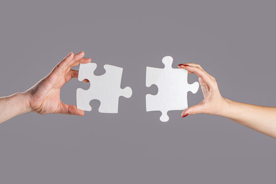 Hands connecting puzzle. Hand of the man and hand of woman fold puzzle, closeup. Puzzles. Man and woman holds in hand a jigsaw puzzle. Business solutions, success and strategy concept