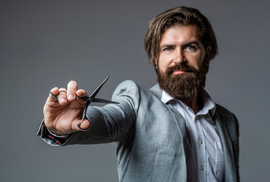 Male in barbershop, haircut, shaving. Bearded man isolated on gray background. Mans haircut in barber shop. Barber scissors, barber shop. Brutal man, moustache