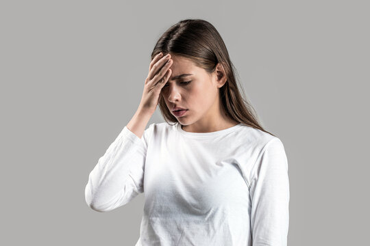 Woman suffering from headache desperate, stressed because pain and migraine. Woman touching her temples feeling stress, on gray background. Girl suffering from headache. Cold symptoms