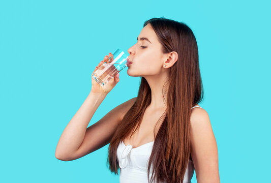 Smiling girl holding transparent glass in her hand of water. Woman drinking from a glass of water. Health care concept photo, lifestyle. Happy woman drinking water