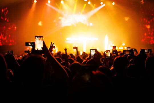Crowd of People Recording Concert on Mobile Phones under Orange Light
