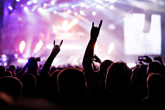 Music Fans Gesturing Rock Signs at Colorful Live Concert