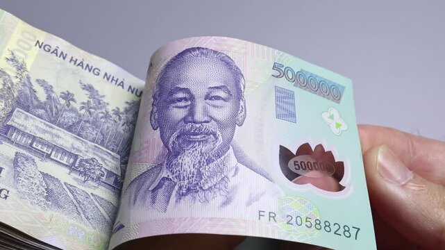Close up view of hand flipping through stack of 500000 Vietnamese dong paper money bills in Vietnam. Concept of dynamic cash counting, business profit calculation, income and high wealth.