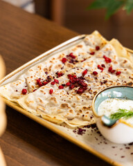 Delicious flatbread with red berries and creamy dip served on a plate © Farhad
