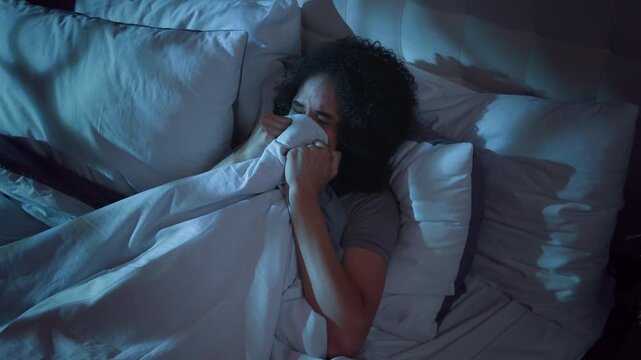Scared stressed African American woman hiding under blanket terror horror feeling stress in bed lying at night suffering with nightmare sleep disorder bad disturbed insomnia afraid female girl scary