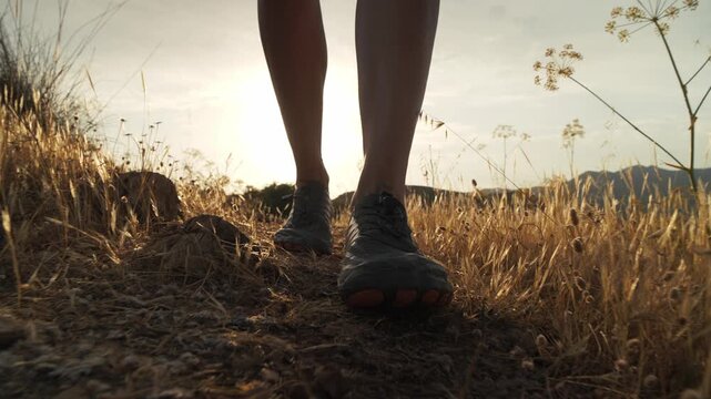 Person embarking on a solo journey, walking barefoot on a dry grassy trail at golden hour, embracing freedom and connection to nature.