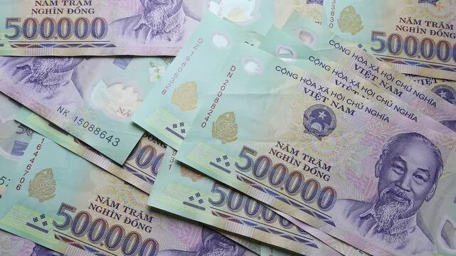 Close up view of hands counting stack of 500000 Vietnamese dong paper money bills. Concept of financial accounting, high income, business profit calculation and domestic cash expenses in Vietnam.