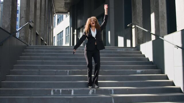 Cheerful Caucasian business woman happy rejoicing with good news holding phone win prize walking down stairs leaving office businesswoman girl female manager agent with smartphone rejoice winning walk