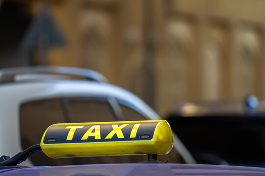 Yellow taxi driving through city street in urban environment, public transportation service, passenger mobility, metropolitan traffic, and everyday commuting concept.