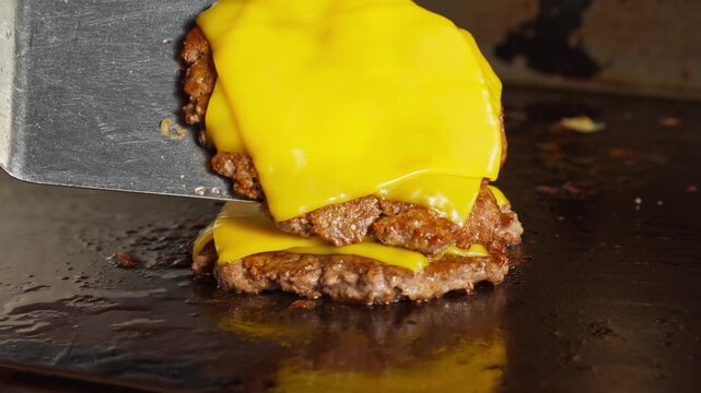 Double cheeseburger assembly, stacking Melted cheese burger patties on griddle