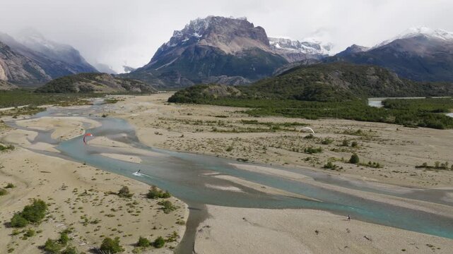 Paragliders flying above R&iacute;o de las Vueltas near El Chalt&eacute;n, Santa Cruz, Argentina, featuring braided glacial channels, gravel and the Fitz Roy massif rising above Southern Andes, parallax aerial shot
