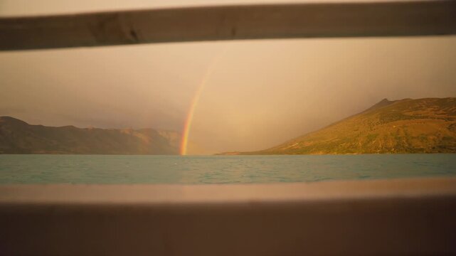 Lago Argentino, Los Glaciares National Park, Santa Cruz, Argentina, featuring a rainbow illuminated by low evening sunlight above glacial waters and Patagonian mountain slopes, push in tracking