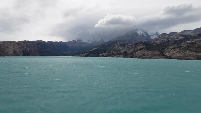Lago Argentino, Los Glaciares National Park, Santa Cruz, Argentina, featuring turquoise glacial waters, granite Andean ridges, snowfields and storm clouds along the Patagonian mountain front, static