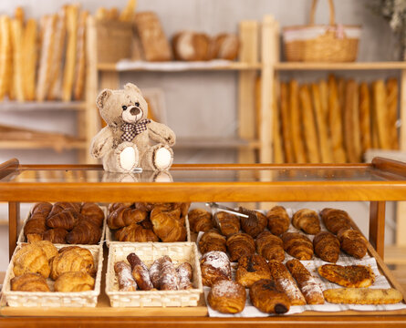 Toy bear is placed on glass display case with pastry, decor of interior space to attract attention