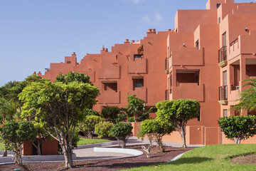 Naklejka premium Modern residential complex featuring landscaped gardens, palm trees and sunny surroundings. Ideal concept for travel, accommodation and vacation rental.