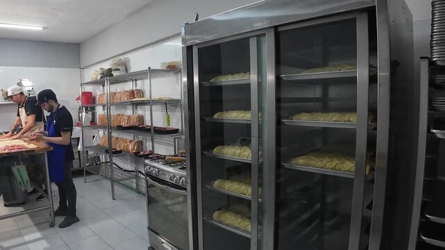 Wide shot hygienic bakery workspace showing skilled chefs crafting baked goods, highlighting the organized process of professional food preparation