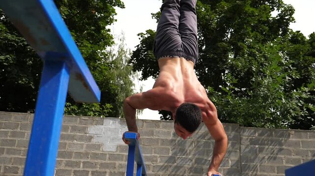 Sportsman performing dynamic handstand push-up training on parallel bars, showcasing strength and balance in a progressive workout sequence with vibrant greenery in the background