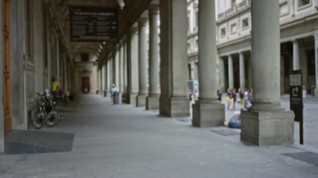 Florence colonnade with soft blurred background along a covered street arcade and stone columns; background copyspace virtual calm.