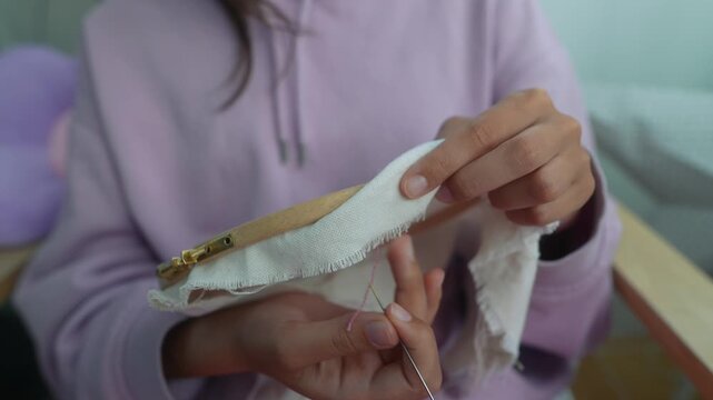 Carefully sewing miniature fabric pouch with needle and thread