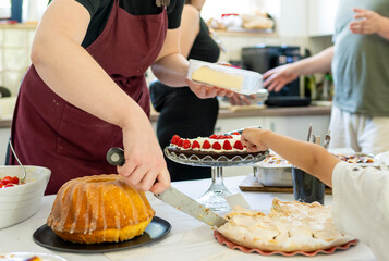 Authentic family dessert buffet with homemade cakes and child reaching for raspberry tart creating...