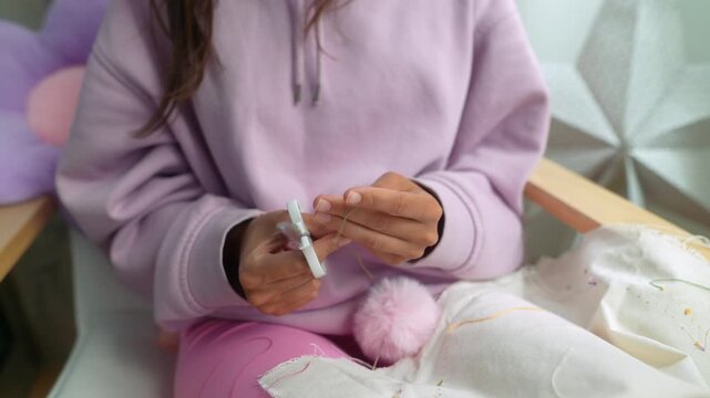 Young girl carefully shaping soft pompom on comfortable cushion