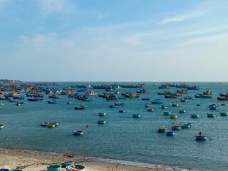 Obraz premium A scenic view of numerous traditional round basket boats, known as thuyen thung, floating in a calm bay near a sandy beach. These unique handcrafted vessels are iconic to the local fishing culture.