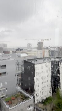 Vertical Rainy Window View of J&auml;tk&auml;saari Rooftops and Construction Cranes