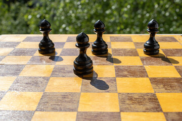 A black pawn stands on the line between squares on a wooden board with others behind, representing a team member at a crossroads, facing a hard choice. © PuzzleSoul