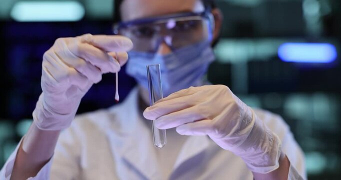 Female scientist puts swab with blood drop sample into test tube in lab. Forensic expert prepares specimen for DNA analysis in police laboratory