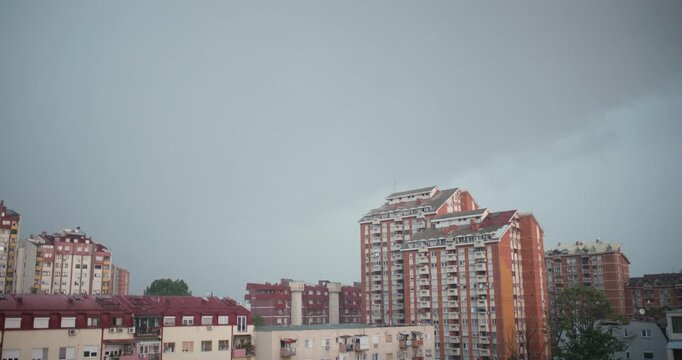 Moody urban cityscape with a distant thunderstorm and rain approaching over redbrick apartment towers.